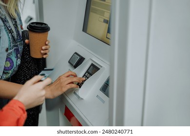 Close-up view of hands inserting a credit card and operating an ATM machine, likely withdrawing cash or checking an account
