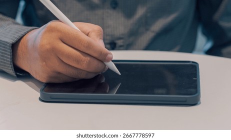 Close-up view of hands interacting with a tablet computer using a stylus.