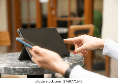 Close-up view of hands interacting with a tablet and smartphone in an outdoor workspace environment. This image is ideal for business, technology, remote working, mobile apps, touchscreen interaction, and digital productivity themes.