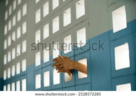 A close-up view of hands reaching through a patterned wall, symbolizing isolation and yearning. The interplay of light and shadows enhances the serene atmosphere.