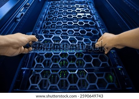 A close-up view of hands removing a server tray from a modern data center rack. The intricate hexagonal design highlights advanced technology and organization.