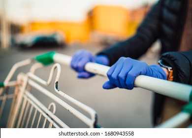 Close-up View Of Hands In Rubber Gloves Pushing Shopping Carts.