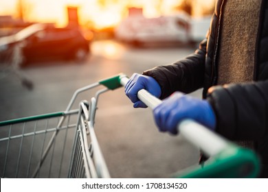 Close-up View Of Hands In Rubber Gloves Pushing Shopping Carts.