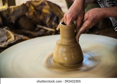 Closeup View Of Hands Of A Senior Asian Potter Forming Clay Into A Pot On A Turntable. Image Of Asian Handcrafts And Manuafacture.