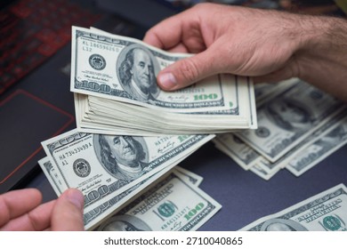 Close-up view of hands sorting multiple 100 bills on a dark desk, illustrating money handling, finance tasks, budgeting, and cash operations. 