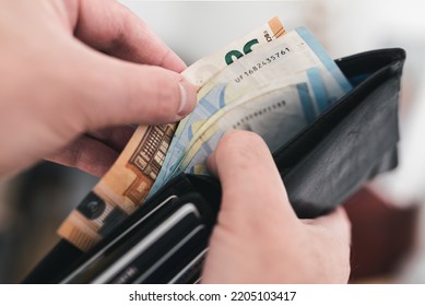 close-up view of hands taking money out of a wallet, spending cash concept - Shutterstock ID 2205103417