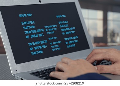 A close-up view of hands typing code on a laptop, showcasing a binary screen. This image reflects technology, programming, and the modern digital workspace. - Powered by Shutterstock - Get 15% off with code: PIKWIZARD15