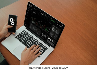  Close-up view of hands using a laptop and smartphone with digital interface displaying financial trading data and automation icons. - Powered by Shutterstock - Get 15% off with code: PIKWIZARD15