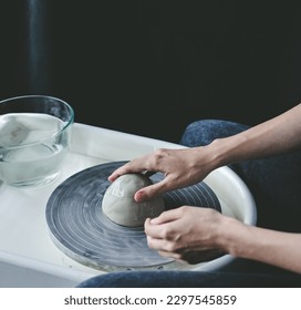 Close-up view of hands working on a potter's wheel with a round piece of clay - Powered by Shutterstock