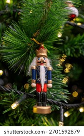 Close-up view of hanging nutcracker, ornaments and other decorations on a Christmas tree.