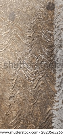 a close-up view of a highly textured, rough surface featuring distinct, repeating wavy or rippled patterns running horizontally.