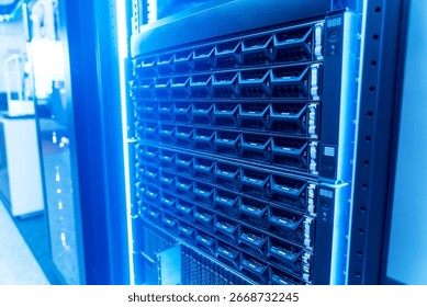 A close-up view of a high-tech server rack illuminated by blue lights, showcasing modern technology used for data storage and network infrastructure solutions.