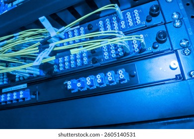 A close-up view of a high-tech server room showcasing vibrant blue lighting over organized network connections, highlighting various cables and components used in data transmission and management.