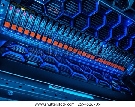 A close-up view of a high-tech server storage unit illuminated by blue LED lights. This modern design showcases an organized array of hardware components within a server rack.