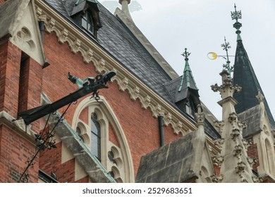 Close-up view of a historic building facade of church Herz Jesu Kirche in Graz, Styria, Austria. Large gargoyle-like sculpture of dragon, perched atop the building. Red brick exterior, ornate windows - Powered by Shutterstock