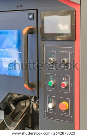 Close-up view of an industrial control panel with multiple red and green buttons, a blue graphical interface screen, orange accents on handles, modern design, comprehensive angle, even lighting, vivi