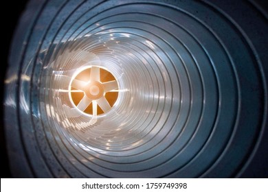 Closeup View From Inside The Galvanized Steel Air Duct On The Exhaust Fan In The Background Light, The Front And Back Background Is Blurred With A Bokeh Effect