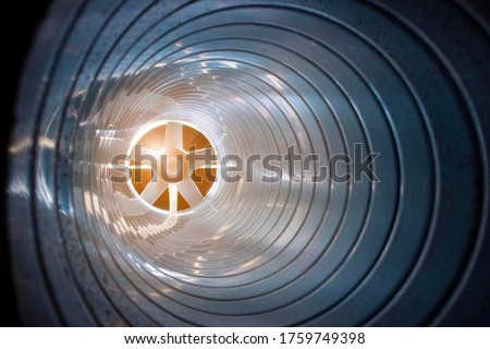 closeup view from inside the galvanized steel air duct on the exhaust fan in the background light, the front and back background is blurred with a bokeh effect