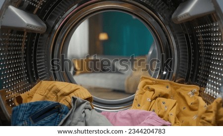 Closeup view from inside the washing machine, full of colorful clothes inside and opened door