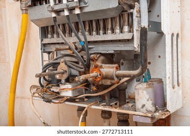 Close-up view of the internal components of an old, dirty, and corroded instantaneous water heater, indicating a need for repair or replacement