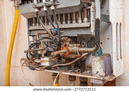 Close-up view of the internal components of an old, dirty, and corroded instantaneous water heater, indicating a need for repair or replacement