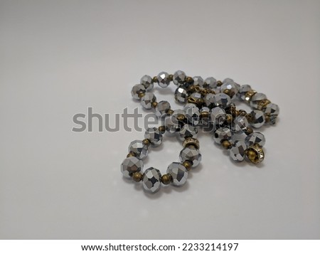Closeup view of Islamic prayer beads made from silver painted plastic isolated on white background.