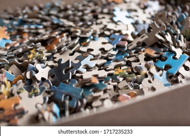 A Closeup View Of A Jigsaw Puzzle Box And Its Many Pieces.