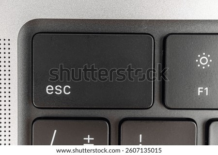 Close-up view of a keyboard corner, with Esc key highlighted Partially visible keys and power button Suggests navigation or shortcuts in marketing context Compact layout suggests its for a laptop