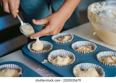 Close-up View Of Kid's Hands, Filling Cupcake Forms With Dough Ingredients Helping Mother To Prepare Holiday Table. Cooking Utensils. Parent, Child. Happy