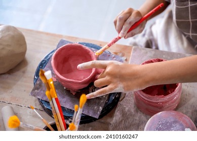 Closeup view of kids making a craft of a porcelain mug from wet clay. Pottery craft clay concept - Powered by Shutterstock