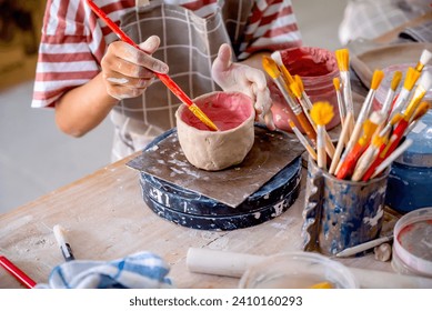 Closeup view of kids making a craft of a porcelain mug from wet clay. Pottery craft clay concept - Powered by Shutterstock