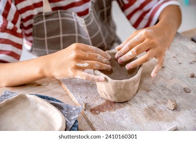 Closeup view of kids making a craft of a porcelain mug from wet clay. Pottery craft clay concept - Powered by Shutterstock