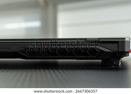 Close-up view of a laptop's side, emphasizing ventilation and design in a stylish workspace environment.
