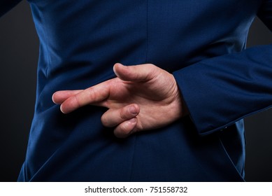 Closeup view of liar businessman standing with crossed fingers behind his back