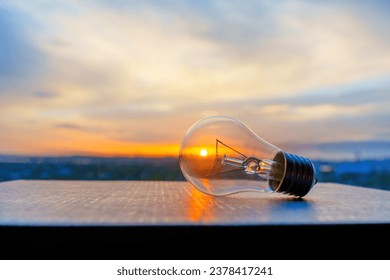 Close-up view a light bulb with dramatic sky and setting sun glowing through. Solar energy related concept. - Powered by Shutterstock
