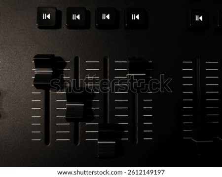 Close-up view of a lighting control panel with sliders and buttons in dark room.