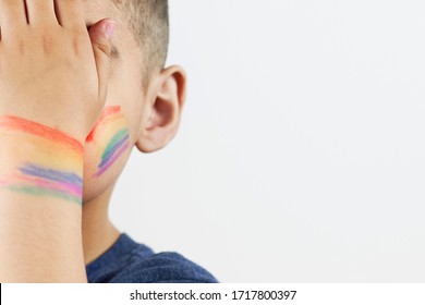 Nahaufnahme der kleinen Jungenhalbe mit gemalter Regenbogenflagge auf den Wangen. Halbbild-Porträt von LGBTQ-Familienkindern. Hochzeitstag, LGBT-Familie, Rechte und Gleichstellungskonzepte
