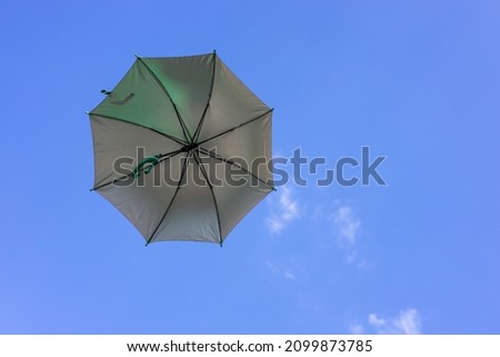 A close-up view from the low, a beautiful opaque bronze umbrella floating freely in the blue sky in the springtime sunlight of the Thai countryside.