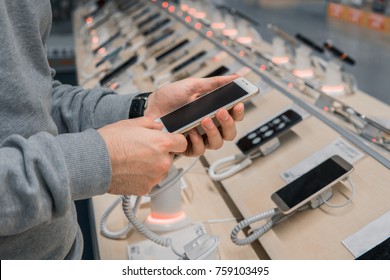 Closeup View Of Male Customer Hands, Choosing White Smartphone In The Mobile Phone Store. Difficult Decision. Various Choice