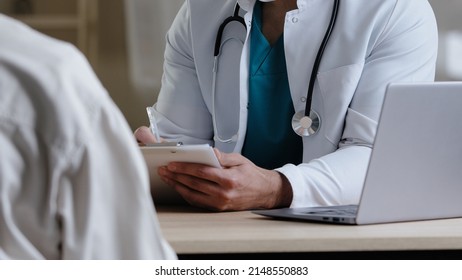 Close-up View Male Unknown Doctor Therapist Man In White Medical Uniform Sit At Desk Consult Patient Complaints Give Advice Intern Medical Colleague Explain Treatment Schedule Handwriting Prescription