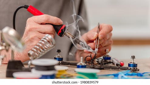 Closeup view of man hands during quadcopter repairing process using soldering iron for wires