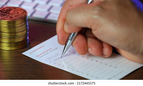 A closeup view of a man writing his secret cryptocurrency wallet recovery "seed" phrase on a note card.  	