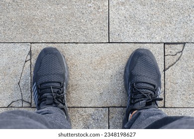 Close-up view of a man's feet wearing shoes standing on a paving stone road texture. Paving stones, paving background. Top view of men's feet. - Powered by Shutterstock