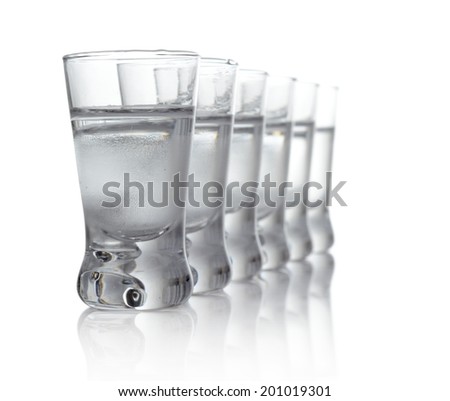 Close-up view of many glasses of vodka standing isolated on white