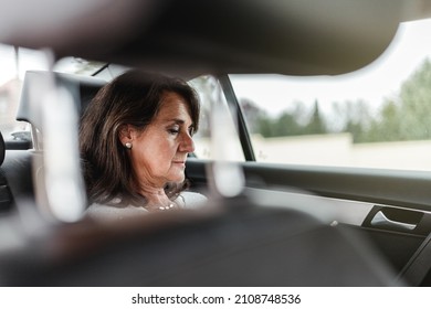 Close-up View Of Mature Hispanic Woman Face On A Taxi Backseat Looking Her Phone