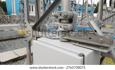 Close-up view of a mechanical linkage and operating mechanism on a control cabinet at a high-voltage electrical substation. Power distribution infrastructure and galvanized steel structures.