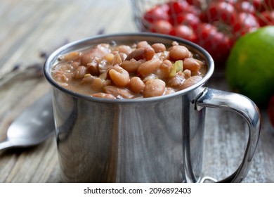 A Closeup View Of A Metal Cup Of Cooked Pinto Beans.