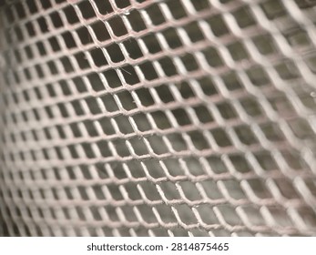 Close-up view of a metallic mesh grid with a shallow depth of field, creating an abstract background texture