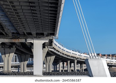 Closeup view of a modern bridge understructure with support pillars and cables, presenting intricate architecture against blue sky in an urban setting. Western High-Speed ​​Diameter, Saint Petersburg