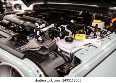 A close-up view of a modern car engine bay, showcasing various components including the engine block, battery, wiring, and air intake. Perfect for automotive and mechanical themes. - Powered by Shutterstock